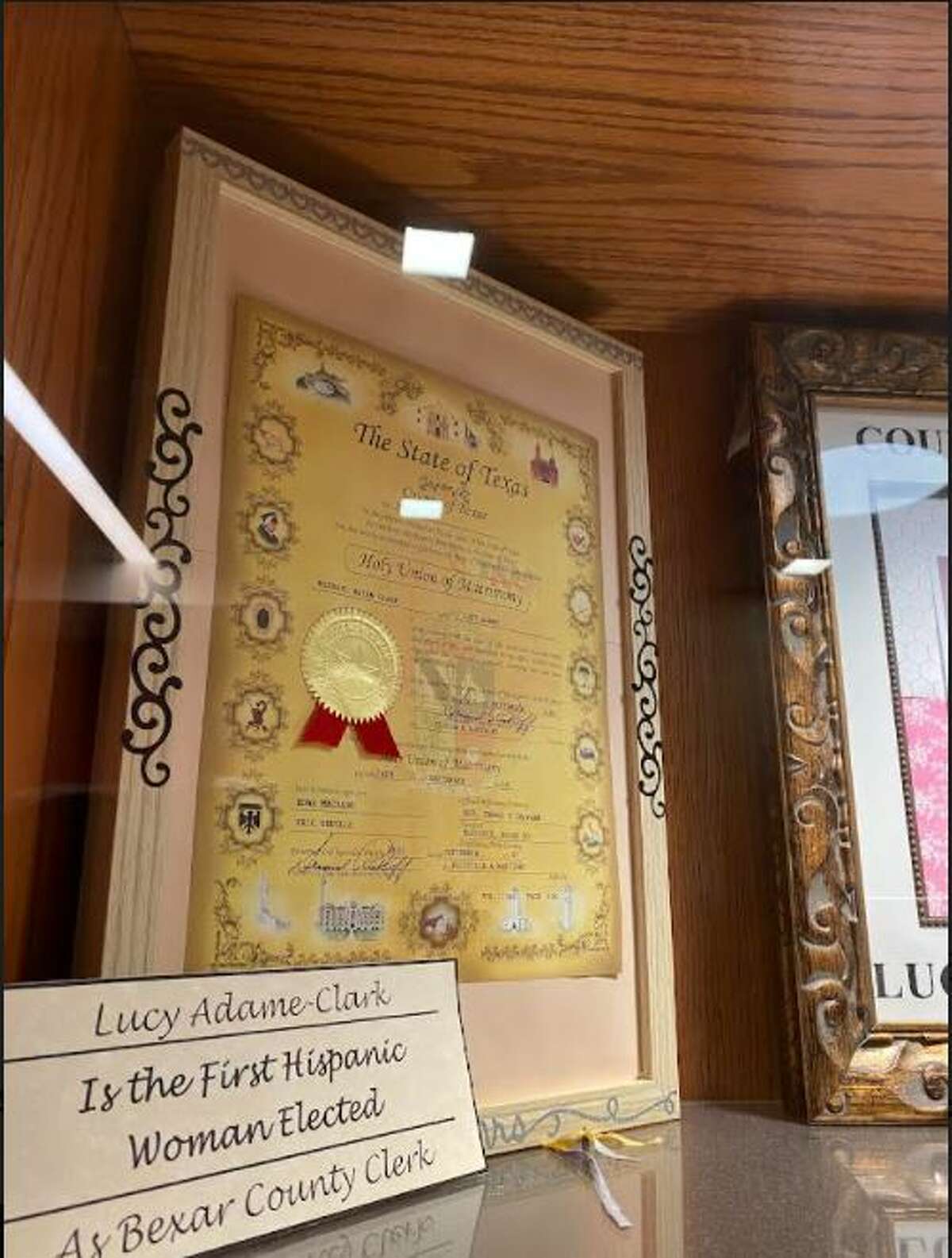 Clerk Lucy Adame-Clark's own marriage license is displayed in a case in the basement next to a portrait of her and her husband Michael. It’s just a few steps away from the window where couples submit their marriage license.