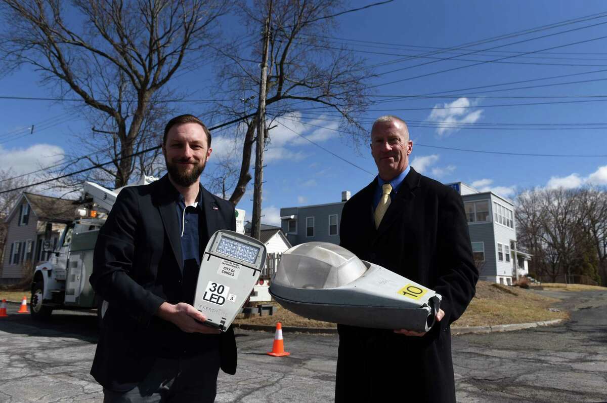 Cohoes City Planner Joe Seman-Graves, left, holds one of the new LED street lamps that are being installed around the city and Mayor Bill Keeler hold an old lamp that was removed, right, on Tuesday, March 8, 2022, on Third Street in the Van Schaick Island neighborhood of Cohoes, N.Y. Changing out city street lights is providing financial support for Cohoes environmental and building plans.