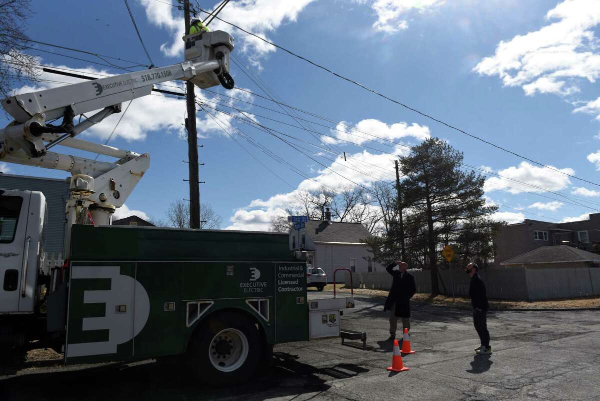 Cohoes Mayor Bill Keeler, left, and City Planner Joe Seman-Graves, right, oversee the installation of a new LED street lamp on Tuesday, March 8, 2022, on Third Street in the Van Schaick Island neighborhood of Cohoes, N.Y. Changing out city street lights is providing financial support for Cohoes environmental and building plans.