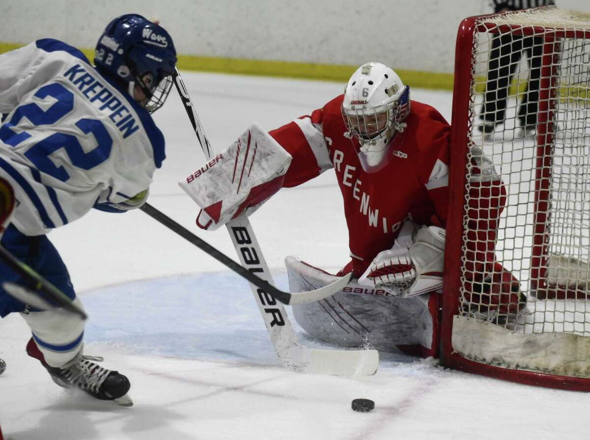 Darien’s Graham Kreppein (22) shoots while Greenwich goalie Cole Studwell defends the net during the first round of the CIAC Division I boys hockey tournament on Tuesday at Darien Ice House.