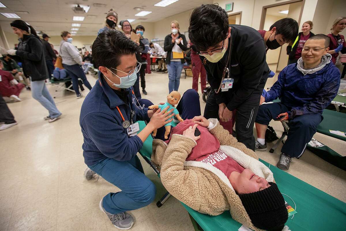 Texas A&M medical student Andrew Wang, left, and Timothy Fan present her “newborn” to simulated disaster survivor Dominique Paderin.