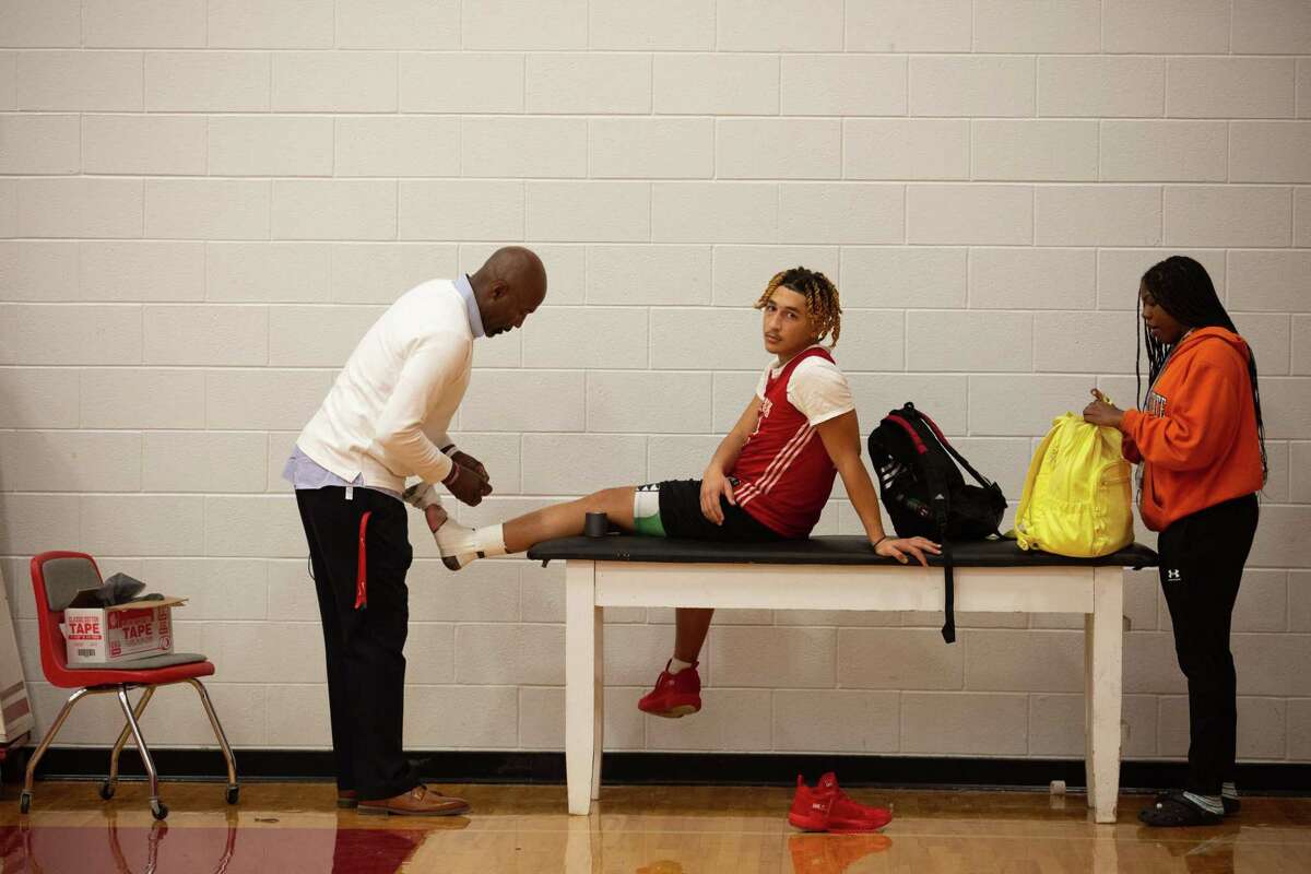 Hitchcock High School boys basketball assistant coach Rogers Davis helps player Kevin Venicle to tape his foot after a practice as the team is preparing for state tournament Tuesday, March 8, 2022, in Hitchcock.