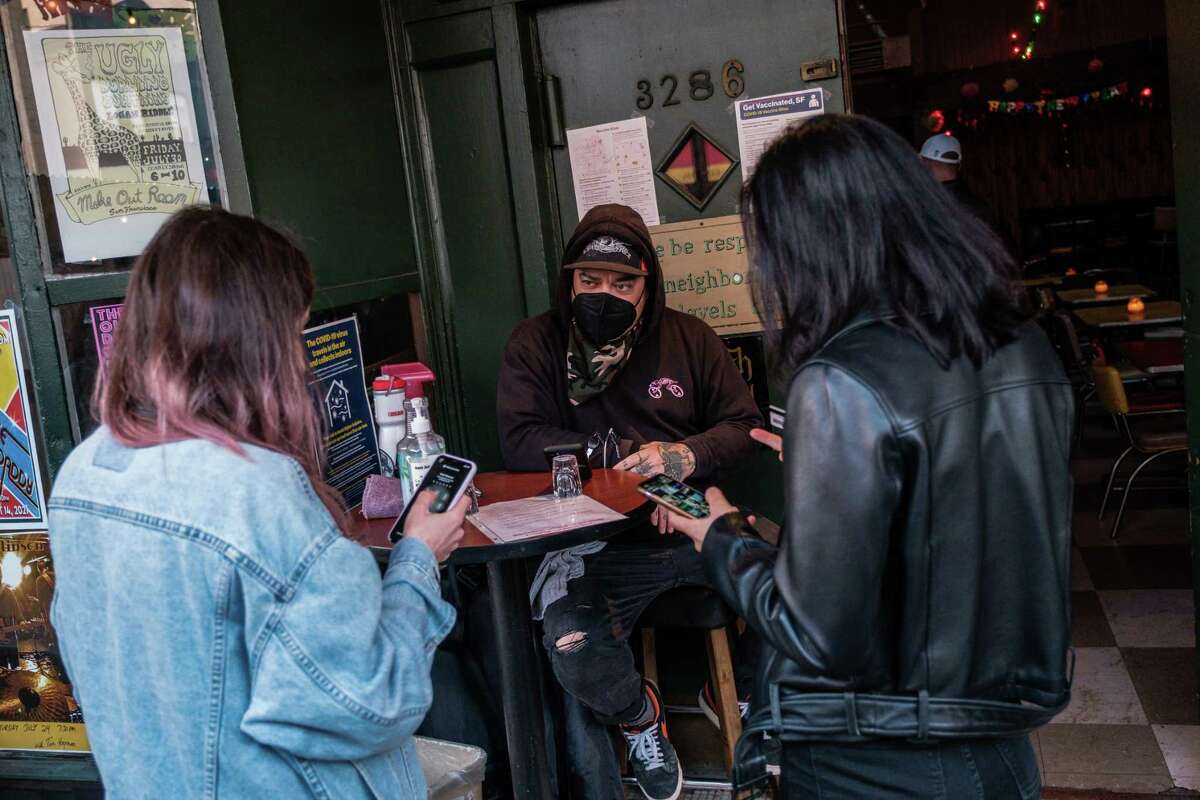 Doorman Jason Voisine waits for two patrons to show him proof of vaccination at the Latin America Club in San Francisco on July 22, 2021. Scenes like this may become a thing of the past when the city lifts its requirement to be vaccinated to enter indoor spaces.