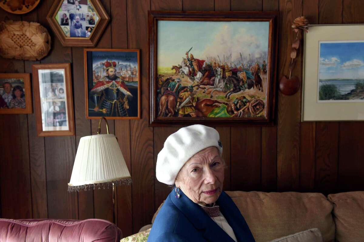 Swyrydenko is photographed in the den of her home in Shelton in front of a wall of historical paintings of Ukraine and family photos.