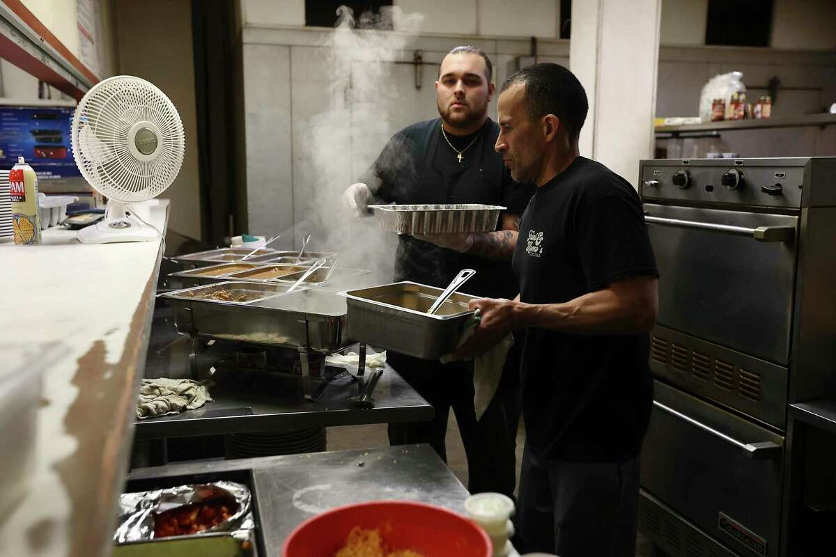 El Ranchito Mexican restaurant's Robby De La Garza (center) and his son, Julian, have to improvise heating up food while the city of Seguin deals with a natural gas outage which could last for days.
