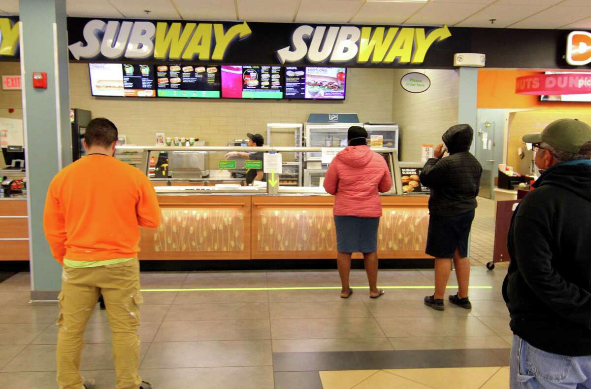 Customers wait on line at a Subway restaurant at the Interstate 95 northbound service plaza in Milford, Conn., on March 2, 2020. A federal judge has ruled that litigation over the tuna in Subway’s products can continue.