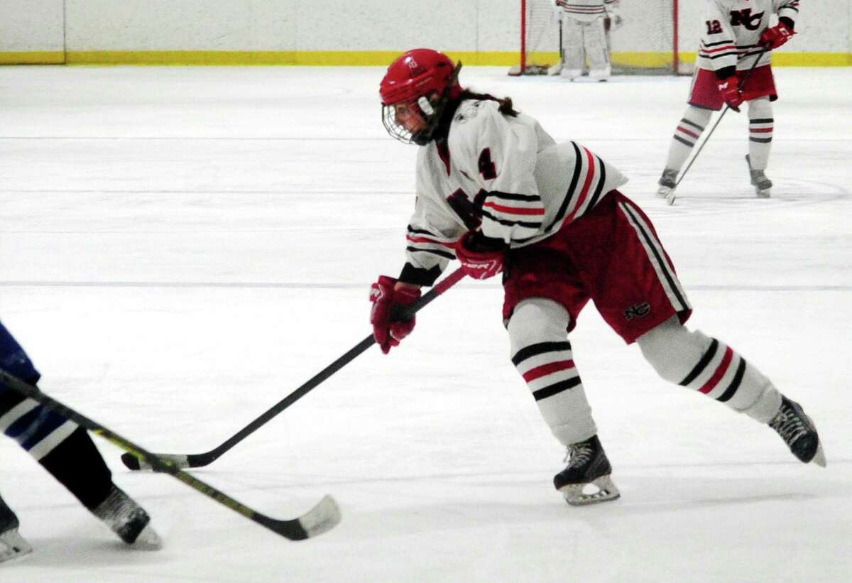 New Canaan's Kaleigh Harden (4) prepares to hit the game winning goal to beat Darien in Connecticut High School Girls Hockey Association state final action at Darien Ice House in Darien, Conn., on Saturday March 9, 2022. New Canaan broke the 3-3 tie in triple overtime.