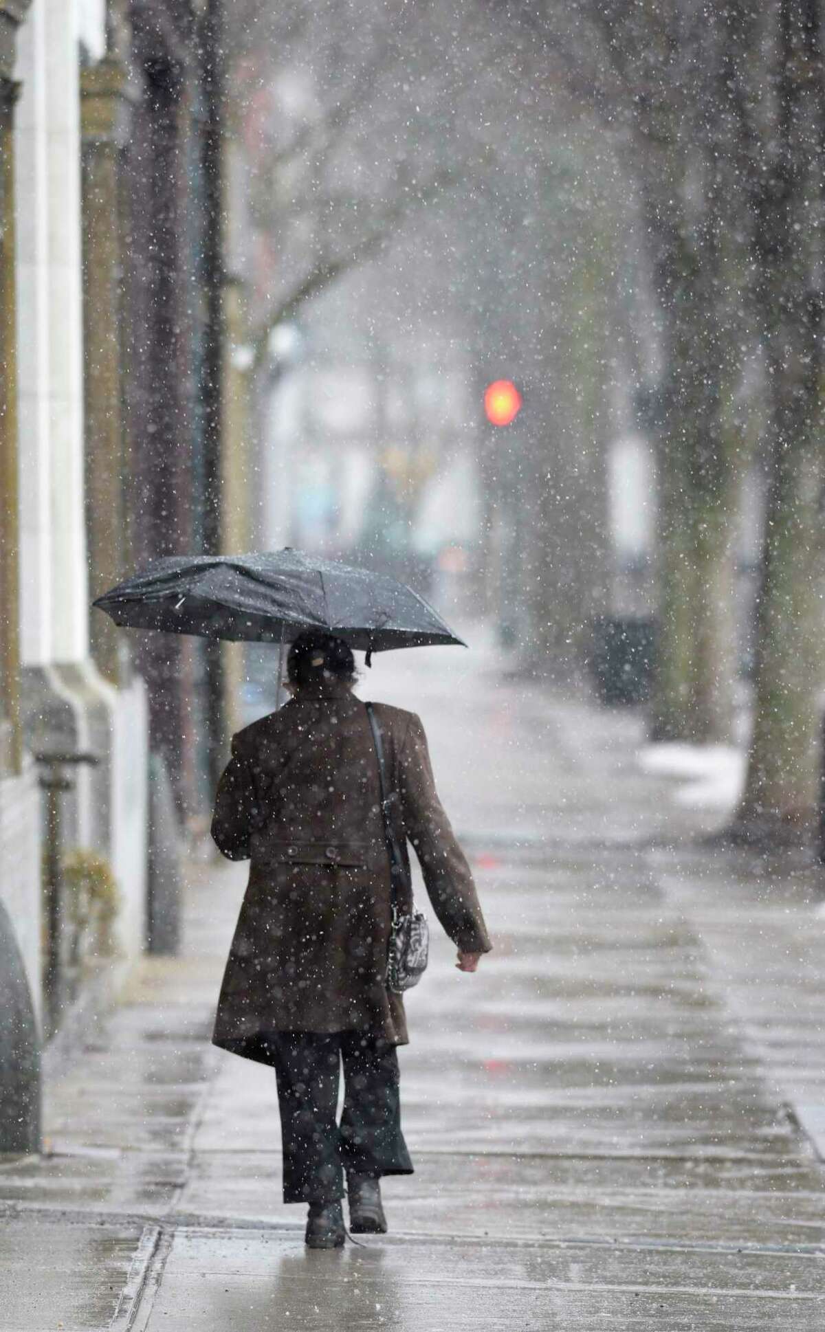 A pedestrian walks along Main Street as a wet snow fell across the Greater Danbury area on Wednesday, March 9, 2022, Danbury, Conn.