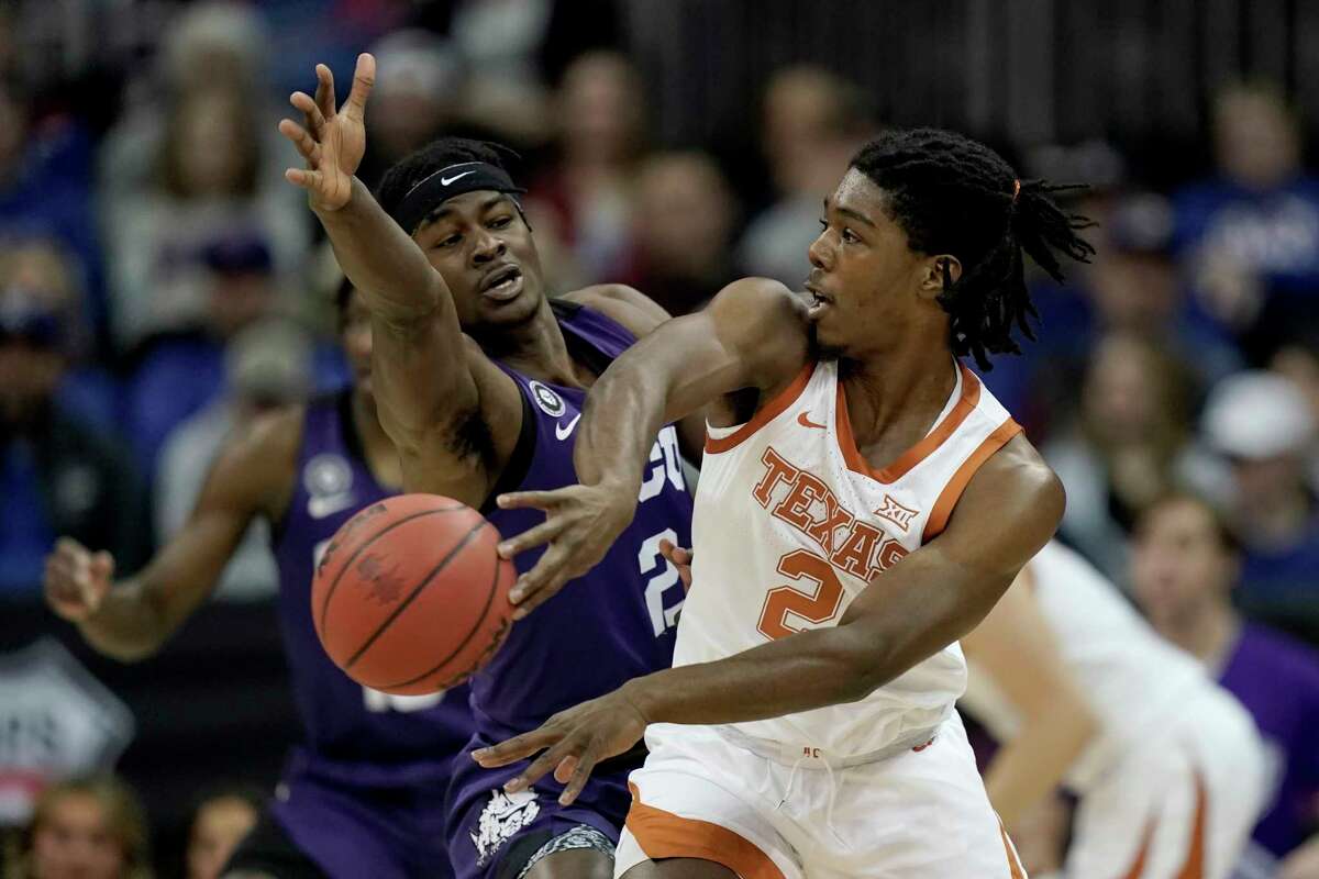 Texas guard Marcus Carr, right, passes around TCU forward Emanuel Miller during the first half of an NCAA college basketball game in the quarterfinal round of the Big 12 Conference tournament in Kansas City, Mo., Thursday, March 10, 2022. (AP Photo/Charlie Riedel)