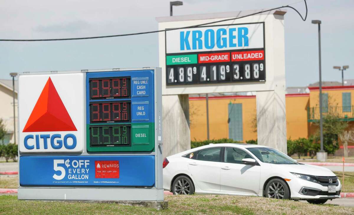 A car passes a pair of gas station signs in Montgomery County showing prices near $4 a gallon, Wednesday, March 9, 2022.