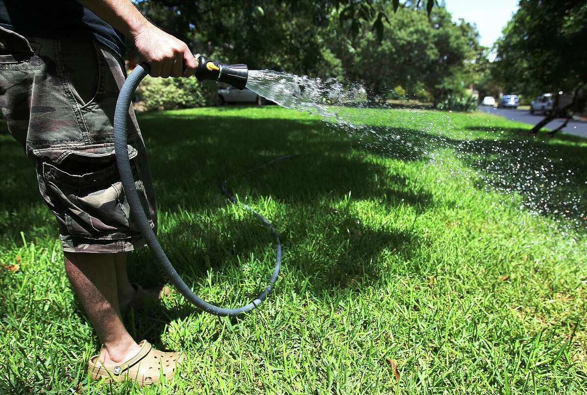 An Alamo Heights resident waters his recently re-sodded yard Aug. 15, 2013.