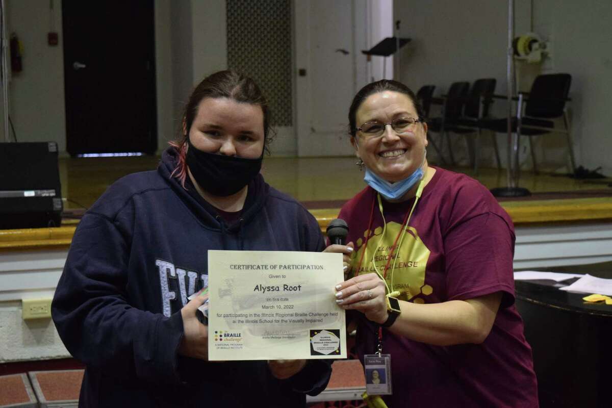 Senior Alyssa Root (left) shows her certificate of participation. Root placed first in the Braille Challenge at the Illinois School for the Visually Impaired.