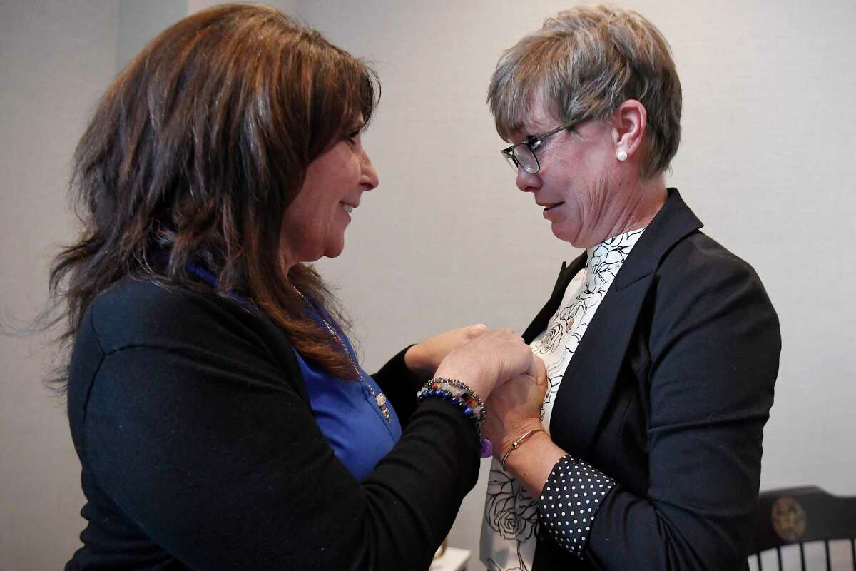 Liz Fitzgerald of Southington and Paige Niver of Manchester hold hands at the end of a news conference at Connecticut Attorney General William Tong's office, on March 3, 2022, in Hartford, Conn. Fitzgerald lost two sons to opioids and Niver's daughter became addicted to opioids after getting prescribed OxyContin at 14 years old.    