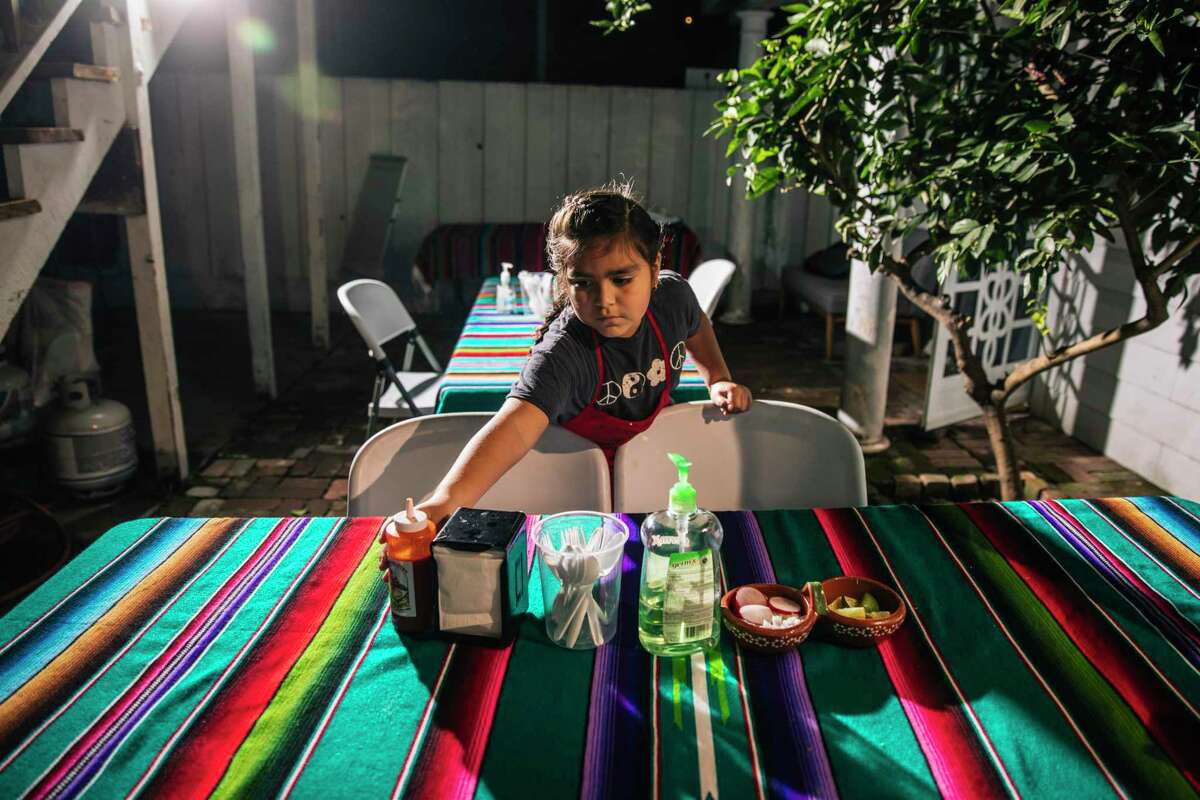 Mia Villaseñor, 8, sets a table while helping at her mother Elvira Varela, at Cenaduria Elvira in Oakland.