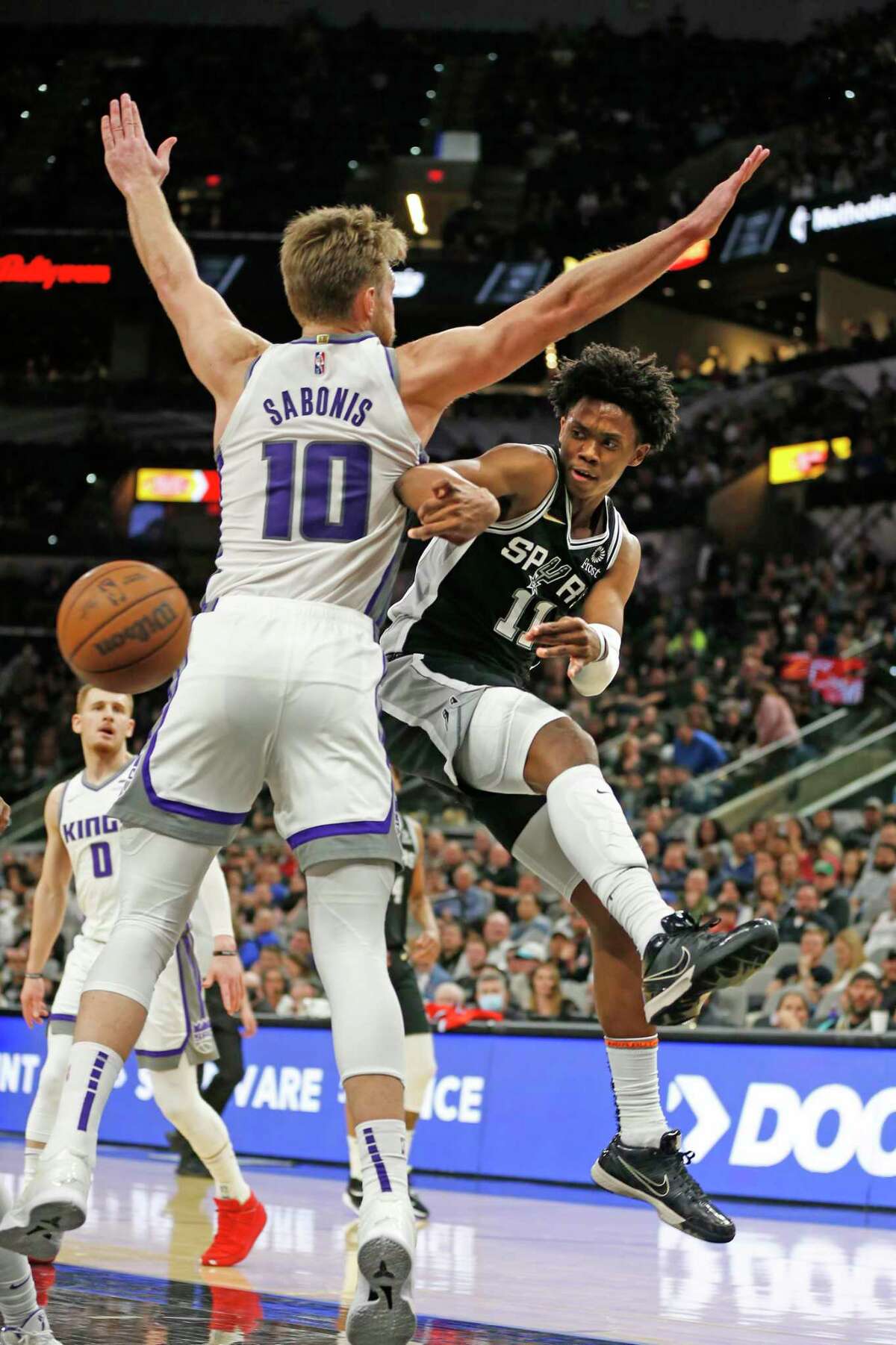 SAN ANTONIO, TX - MARCH 3: Josh Primo #11 of the San Antonio Spurs passes off in front of Domantas Sabonis #10 of the Sacramento Kings in the second half at AT&T Center on March 3, 2022 in San Antonio, Texas. NOTE TO USER: User expressly acknowledges and agrees that, by downloading and or using this photograph, User is consenting to terms and conditions of the Getty Images License Agreement. (Photo by Ronald Cortes/Getty Images)