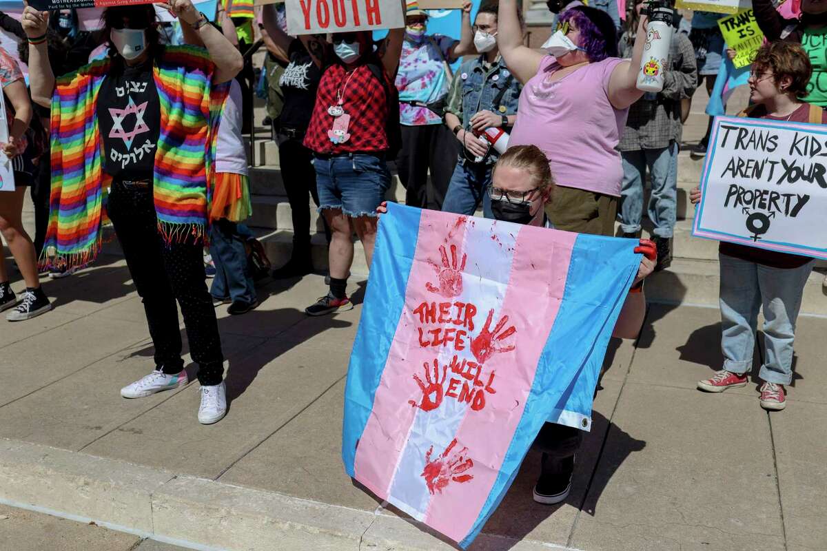 An attendee holds a Transgender pride flag reading “Their lives will end” with fellow attendees during the March for Trans Youth at the Texas Capitol in Austin, Texas, on March 1, 2022. The rally was held in response to Governor Greg Abbott’s recent order seeking to classify gender affirming care for transgender young people as child abuse as well as ordering state child welfare officials to launch child abuse investigations into reports of young people receiving such care.