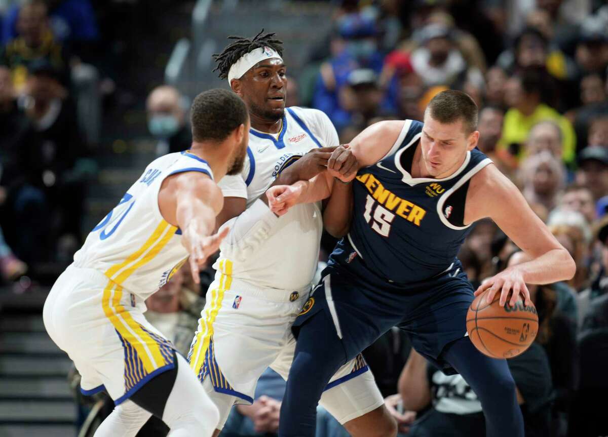 Denver Nuggets center Nikola Jokic, right, is defended by Golden State Warriors guard Stephen Curry, front left, and center Kevon Looney during the first half of an NBA basketball game Thursday, March 10, 2022, in Denver. (AP Photo/David Zalubowski)