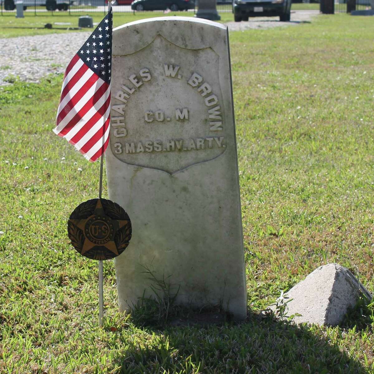 The grave of Charles W. Brown, one of many veterans interred in Humble Cemetery is marked with a commemorative medallion and an American flag.