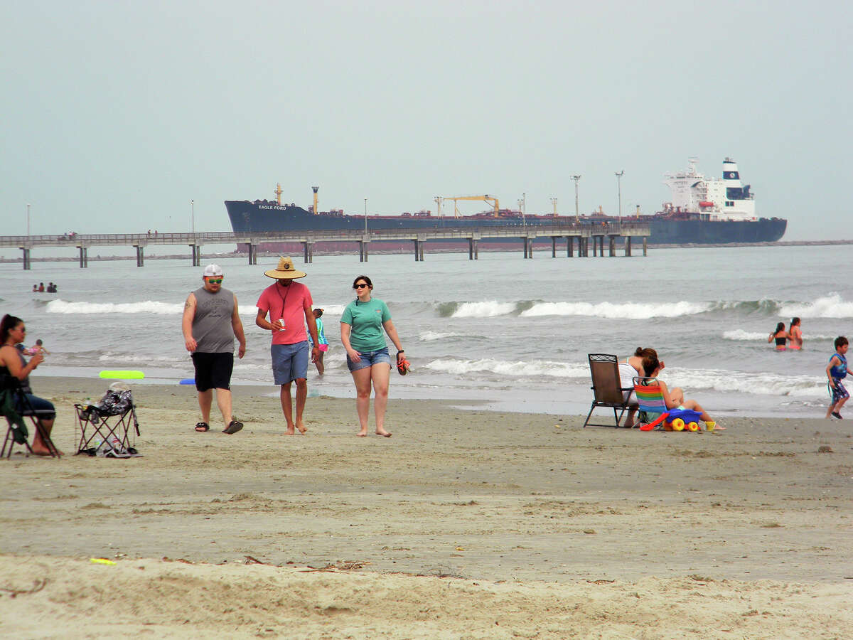 People stroll the Port Aransas beach, enjoying the day despite the lack of sun.