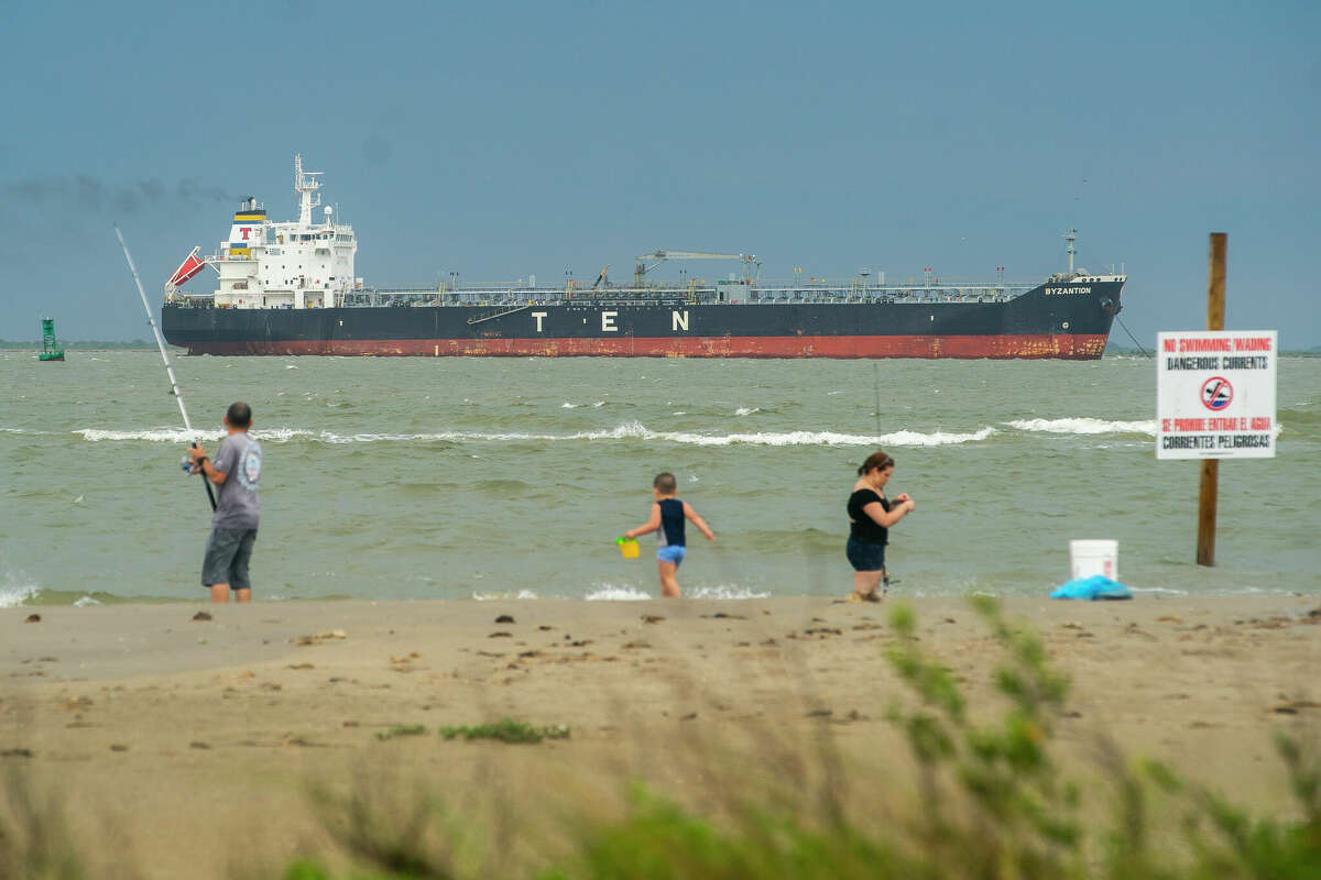 An oil tanker sits offshore between Galveston Bay and the Gulf of Mexico where people fish and enjoy the beach, Friday, May 15, 2020, on the east end of Galveston Island.