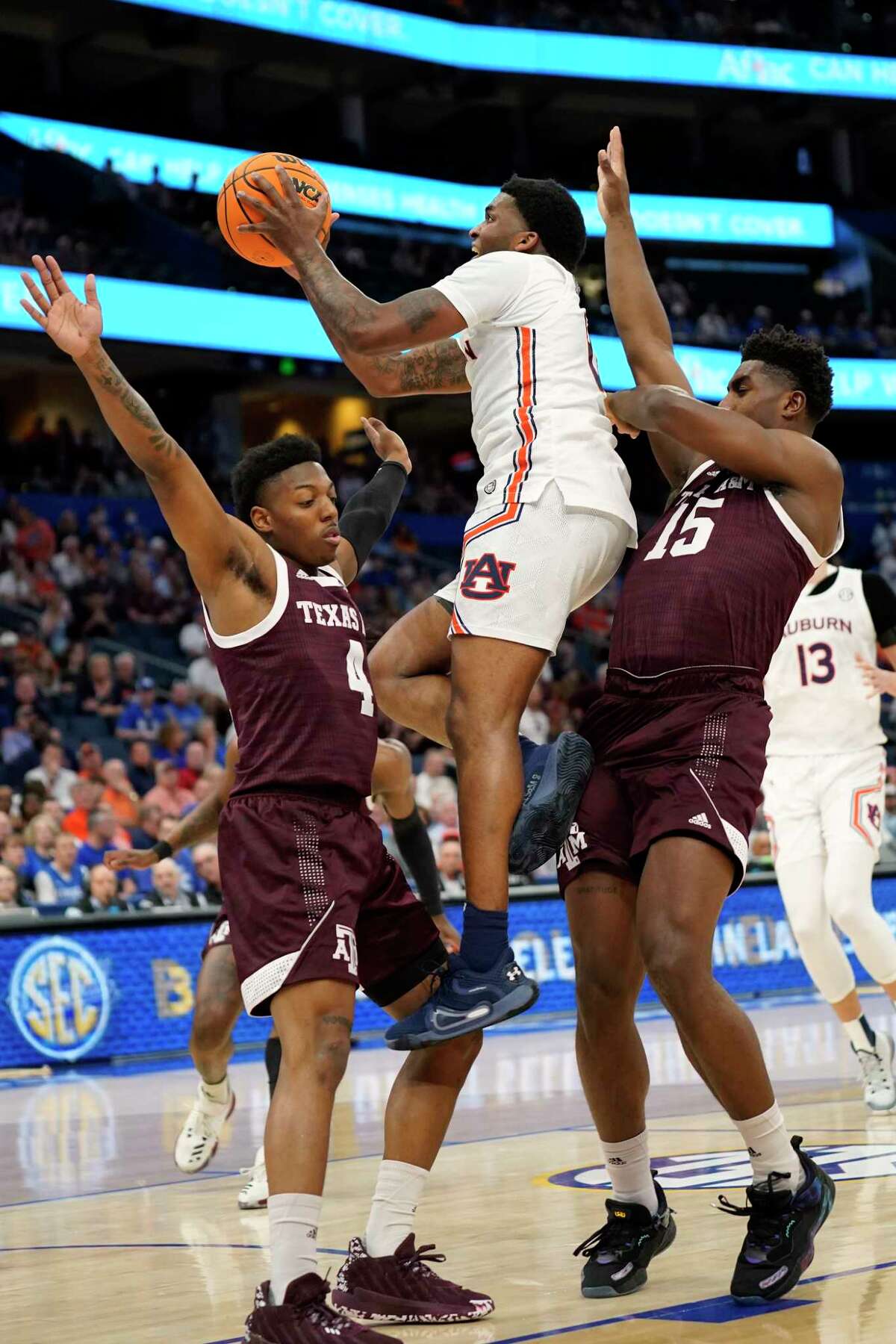 Auburn guard K.D. Johnson (0) puts up a shot betwen Texas A&M guard Wade Taylor IV (4) and forward Henry Coleman III (15) during the first half of an NCAA men's college basketball Southeastern Conference tournament game Friday, March 11, 2022, in Tampa, Fla. (AP Photo/Chris O'Meara)