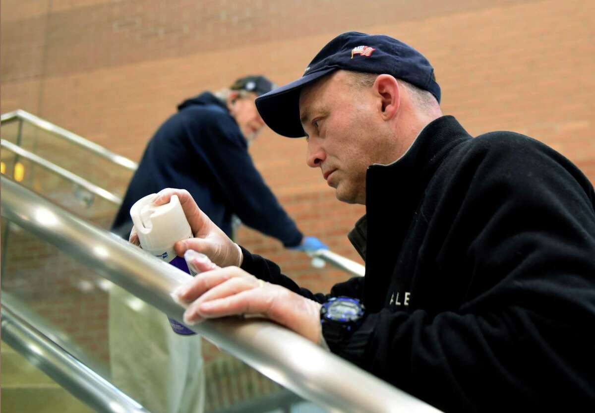 Airport cleaning crew members Rick Stoppard, left, and John Tunney, right, disinfect the handrails at Albany International Airport on Friday, March 6, 2020, in Colonie, N.Y. The airport is taking preventive measure to help combat coronavirus. (Will Waldron/Times Union)