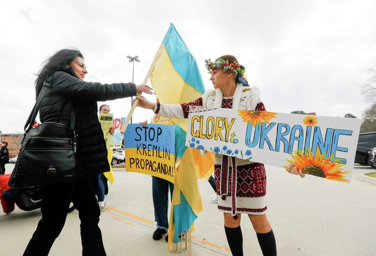 Julia James, right, hands fellow Ukrainian Iryna Gist a flag as veterans and community members gathered at the Montgomery County Veterans Memorial Park to show support for the people of Ukraine, Friday, March 11, 2022, in Conroe.