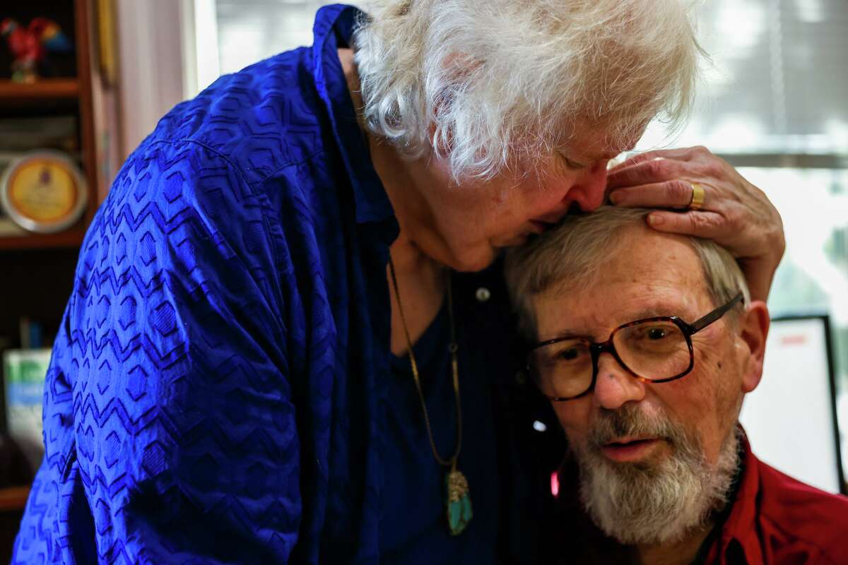Pat McHenry Sullivan, 79, holds her husband John Sullivan as they hang out in their office on Thursday, March 10, 2022, in Oakland, Calif. 