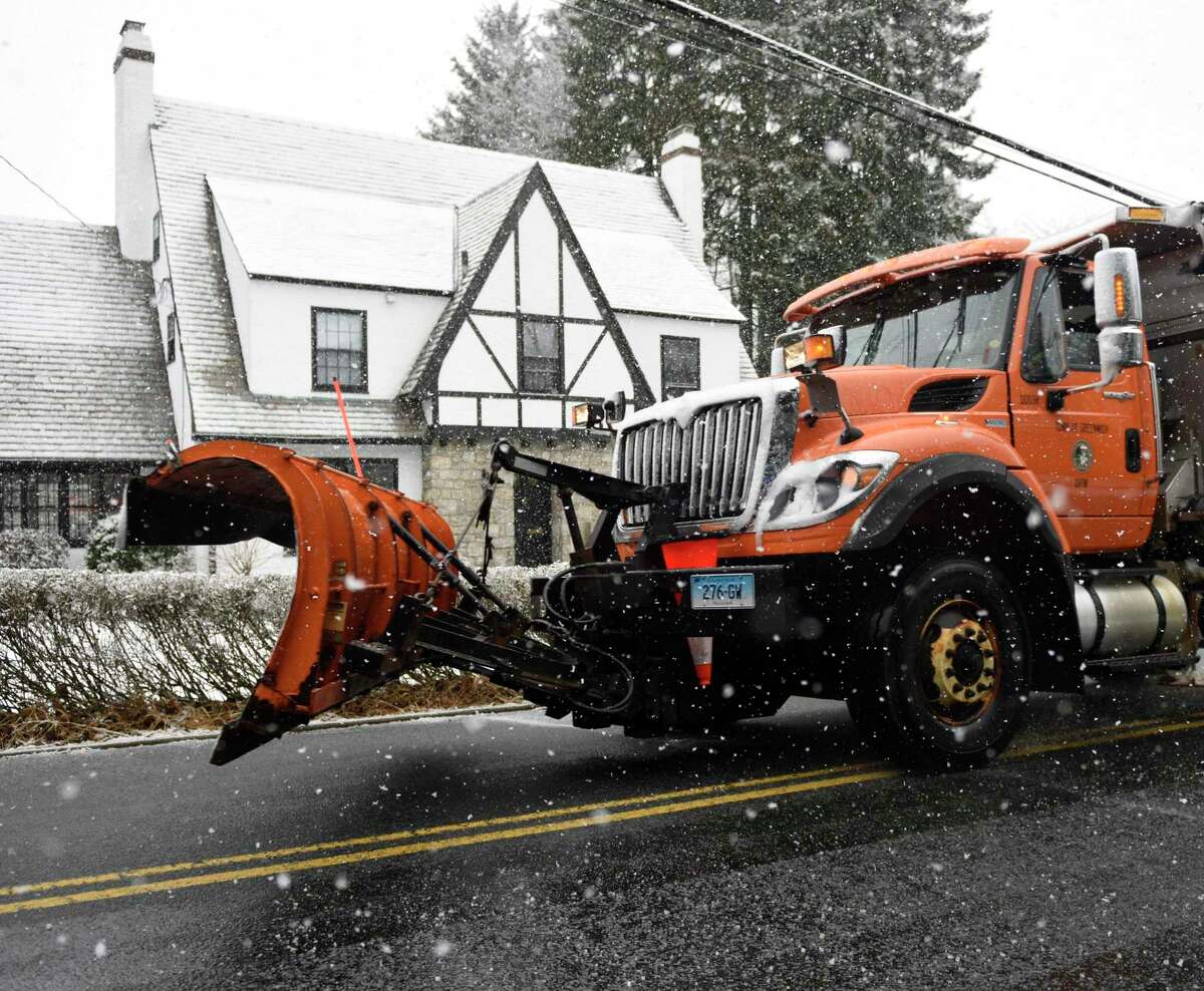 A snow plow spreads salt on a slick street in Greenwich, Conn. Wednesday, March 9, 2022. After starting the week in the 60s, temperatures dropped Wednesday as the town received a light layer of snow. The snow returned to the state on Saturday.