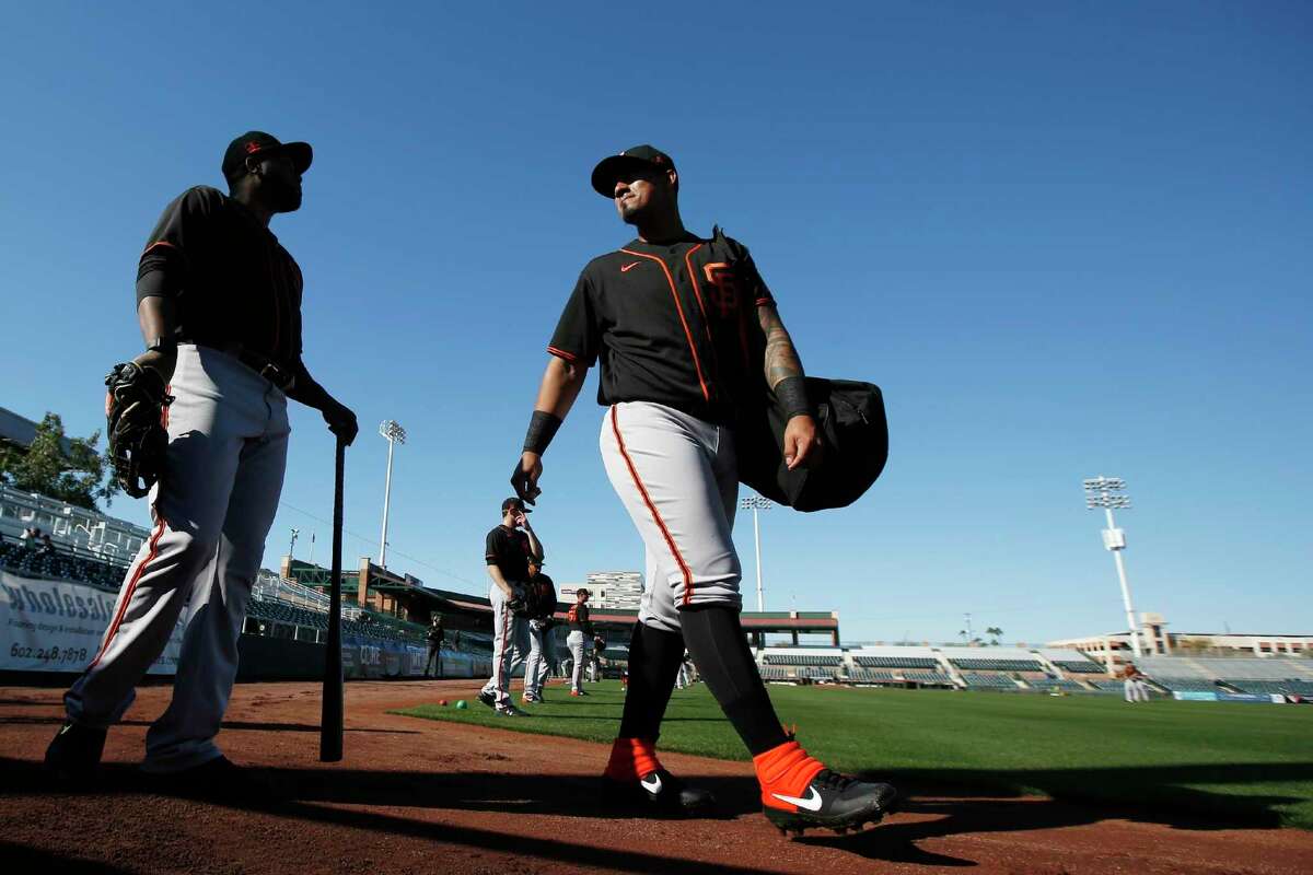 San Francisco Giants catcher Ricardo Genoves, right, talks with minor league coach Mario Rodriguez, left, during spring training baseball workouts for pitchers and catchers Wednesday, Feb. 12, 2020, in Scottsdale, Ariz. (AP Photo/Ross D. Franklin)