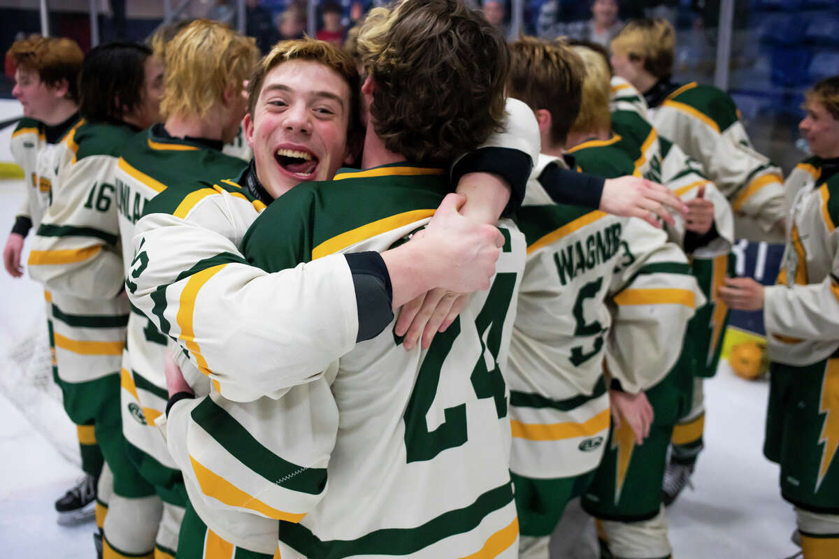 Dow's Zach Pider, left, hugs teammate Jack Smith, center, after the Chargers' 2-0 state finals victory over St. Mary's Saturday, March 12, 2022 at USA Hockey Arena in Plymouth.