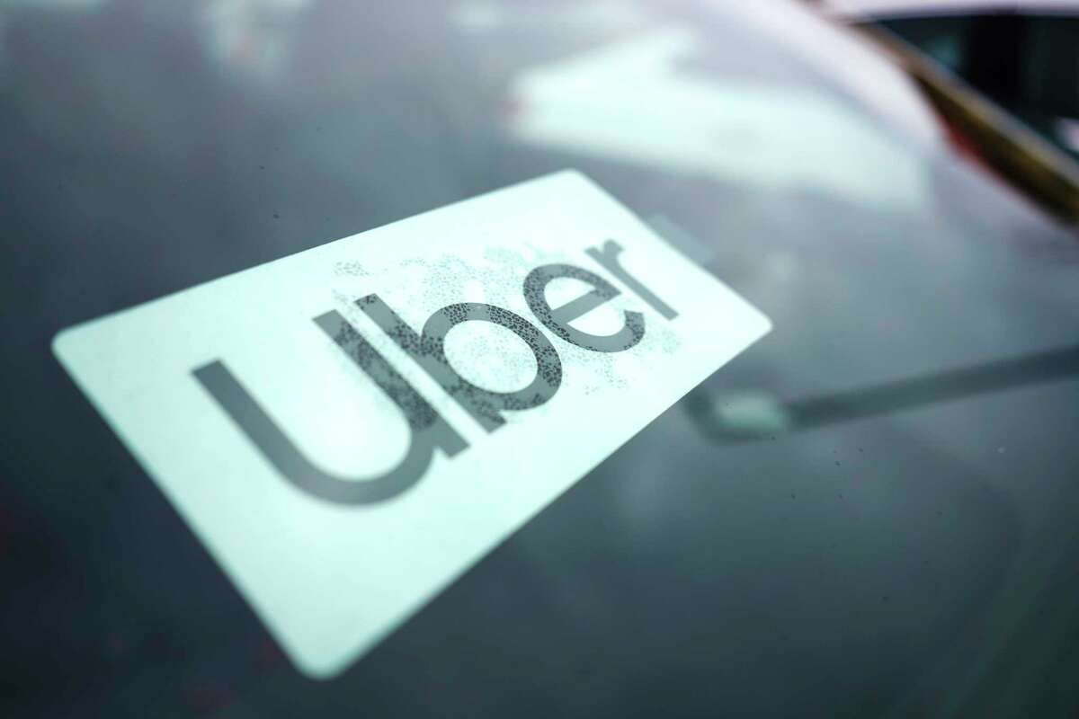 FILE - An Uber sign is displayed inside a car in Palatine, Ill., Thursday, Feb. 10, 2022. Citing record-high prices for gasoline, Uber is charging customers a new fuel fee to help offset costs for ride-hail and delivery drivers. The company announced Friday, March 11, 2022, that the temporary surcharge will be either 45 cents or 55 cents for each Uber trip and either 35 cents or 45 cents for each Uber Eats order, depending on location.