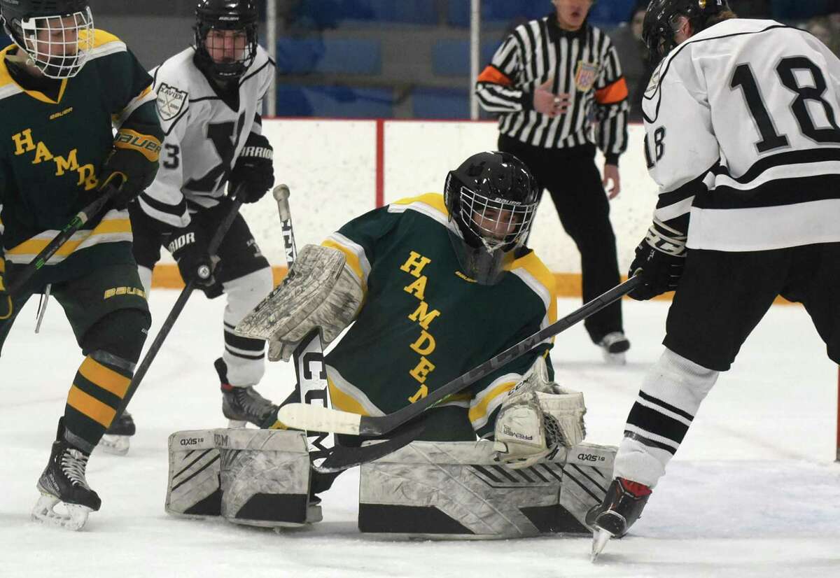 Hamden goalie Brody Sargolini gloves the puck on a shot by Xavier's Dylan Reynolds (18) during a CIAC Division I quarterfinal in West Haven on Saturday.
