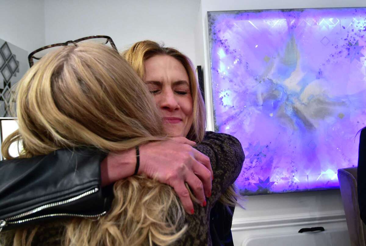 Norwalk artist and gallery owner Oksana Tanasiv, facing camera, receives a hug from Candice Pereira, from nearby business Chloe Winston Lighting Design, after Pereira dropped of a donation during a reception at Oksana Tanasiv gallery in Norwalk, Conn., on Saturday March 12, 2022. Tanasiv hosted the art show featuring the work of several Ukrainian American artists with 100% of sales proceeds going to Ukraine.