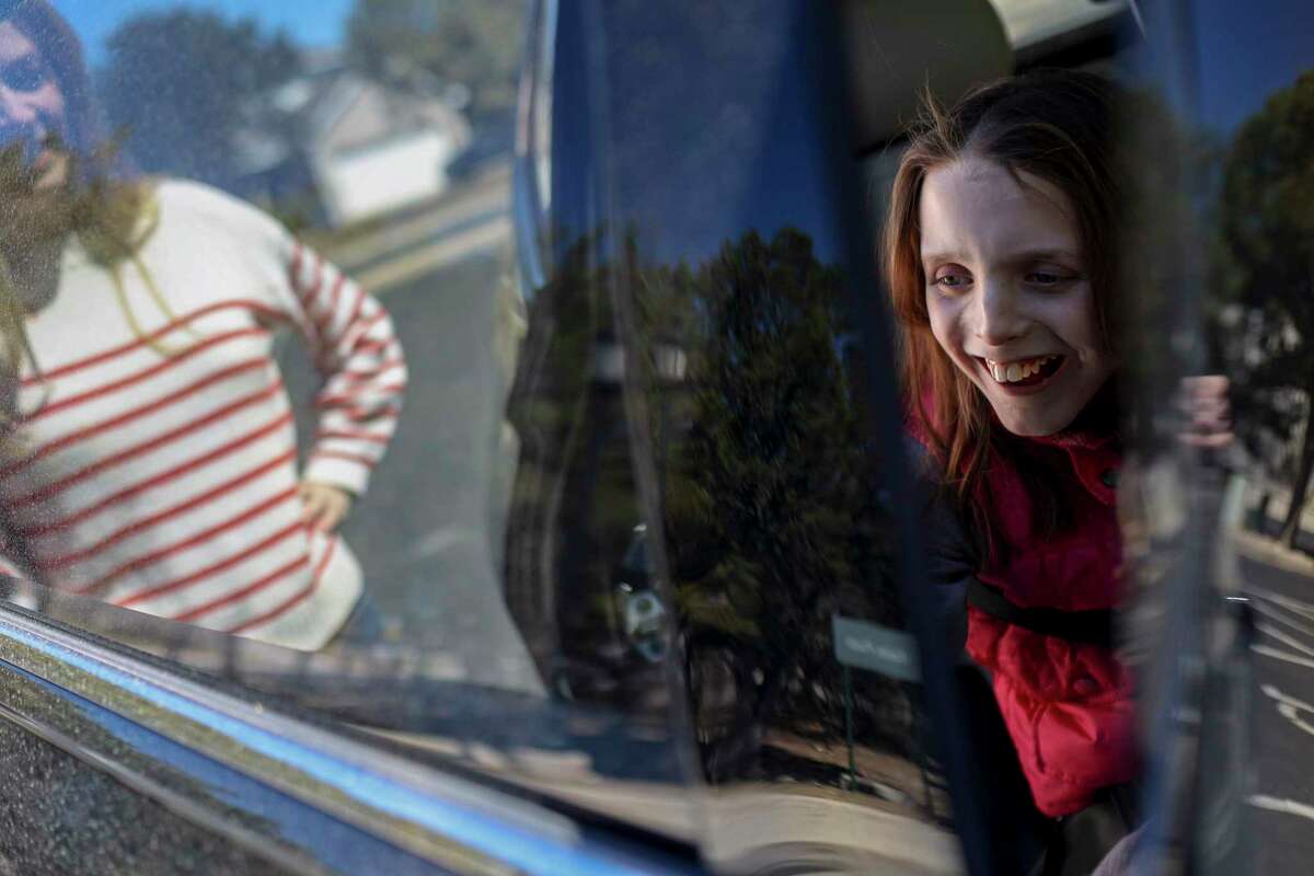 A giggling Reily Starnes, 14, closes the car door on her own as her mom Tiffany Teixidor watches as they leave their neighborhood park in San Antonio on Saturday.