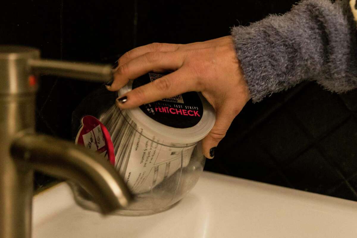 Allison Heller, co-founder of FentCheck, refills a fentanyl test strip dispenser in the bathroom at Rockridge Improvement Club in Oakland, California Thursday, March 10, 2022. Founded in 2019, the Oakland-based harm reduction non-profit is working to provide fentanyl test strips to help drug users to "survive the night" by testing the presence of fentanyl in party drugs to prevent overdose.