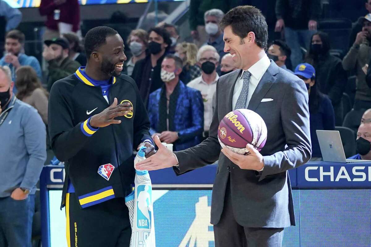 Golden State Warriors forward Draymond Green, left, greets general manager Bob Myers before an NBA basketball game between the Warriors and the Denver Nuggets in San Francisco, Wednesday, Feb. 16, 2022. (AP Photo/Jeff Chiu)