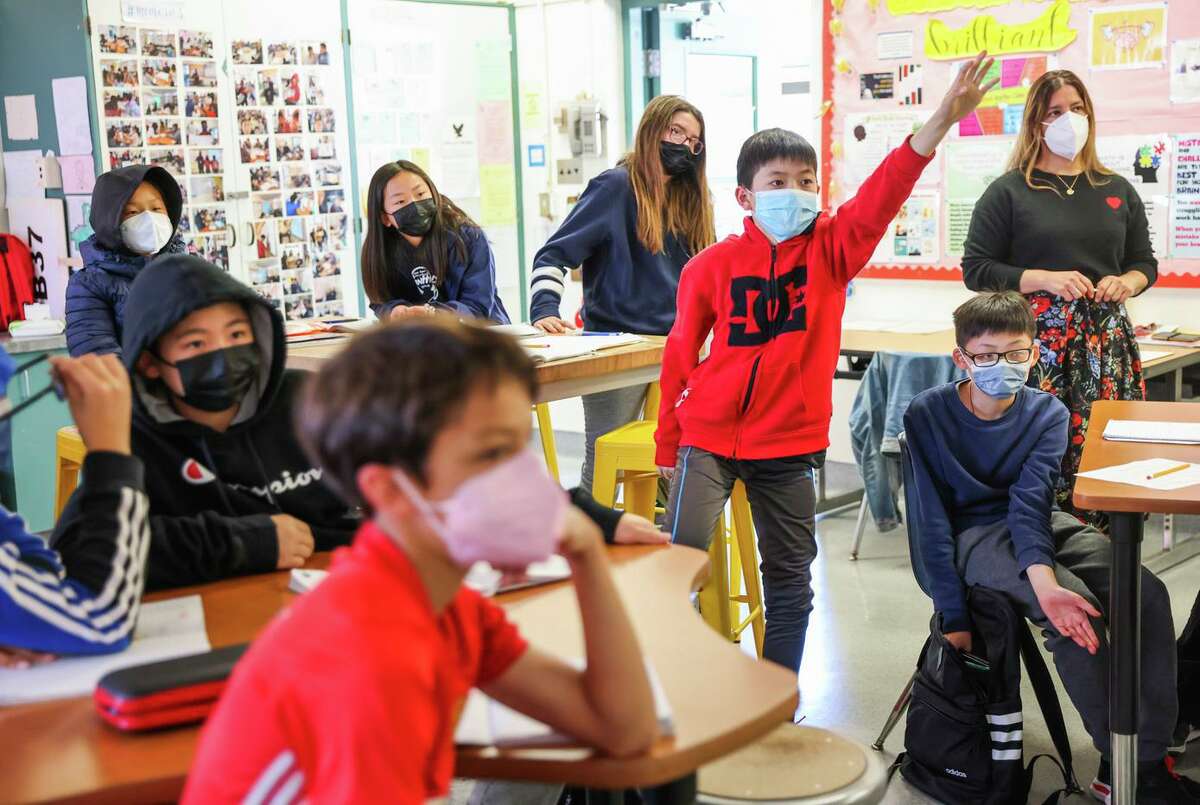 Jaylan Tieu, 11, (center) raises his hand during math class at Hoover Middle School. Some students expressed reluctance to cease a mask-wearing habit that has become a way of life.