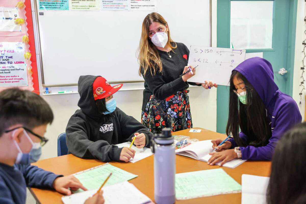 Co-teacher Loyda Narro (center) helps students Jorell Bumagat, 12 (left) and Thiri Naing, 11 (right) during math class at Hoover Middle School on Monday, March 14, 2022 in San Francisco, California. Schools in San Francisco allowed students to go without masks starting Monday.