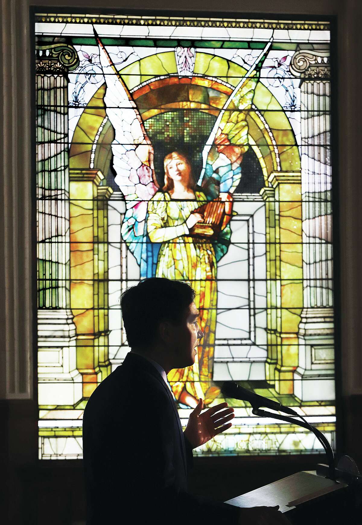 State Sen. Steve McClure, R-Springfield, is silhouetted in front of an 1890s stained glass window in the Reid Memorial Library during an announcement of $37.5 million in state funding to renovate the old main buildings of Lewis & Clark Community College in Godfrey. 