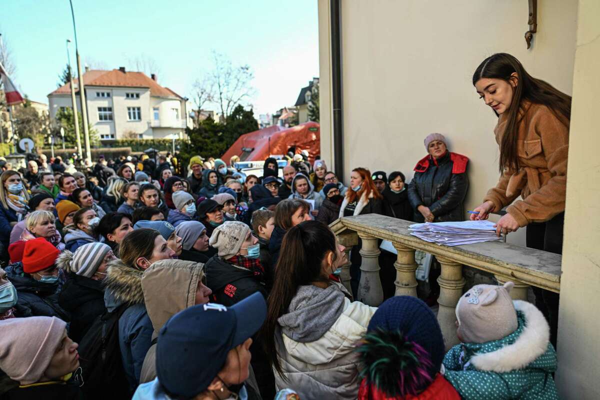 A woman shouts names of registration forms as people who fled the war in Ukraine wait to hear an update on their requests at the Ukrainian consulate courtyard March 14, 2022. in Krakow, Poland. Nearly 2 million refugees from Ukraine have streamed into Poland following Russia’s invasion last month.