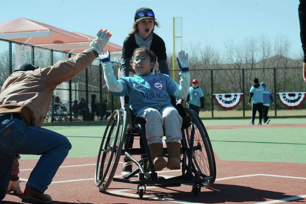Miracle League athlete Lilyana Granados gets a cheer from buddy Madeleine Waguespack and a high five from Pearland Parks and Recreation Department employee Alberto Gonzalez as she crosses home plate to score during the inaugural game at the new Miracle Field at the Sports Complex at Shadow Creek Ranch.