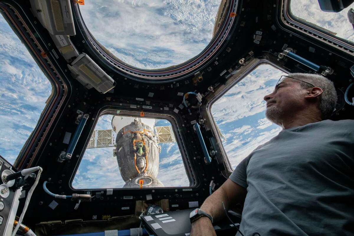 NASA astronaut Mark Vande Hei peers at the Earth below from inside the seven-windowed cupola, the International Space Station's window to the world on Feb. 4, 2022. The Soyuz MS-19 crew ship is docked to the Rassvet module in the background. (Kayla Barron/NASA via AP)