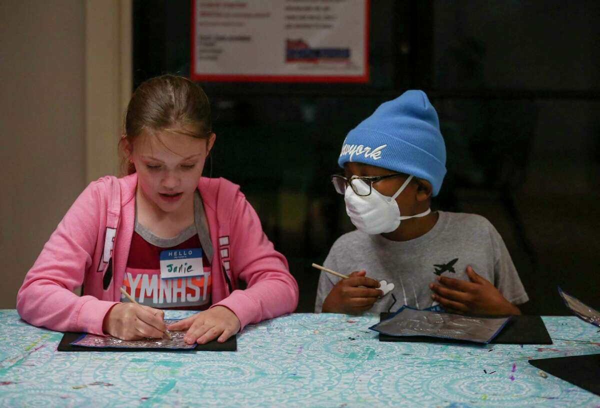Students Janie Jones, 10, left, and Jayden Johnson, also 10, right, talk as they work on their embossed foil pieces during an art class taught by Art Time Party founder Liliya Colston (not pictured) at Champions Cheerleading in San Antonio on Friday.
