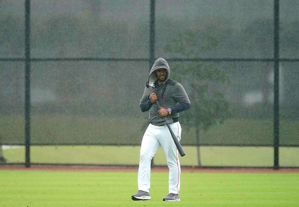 Gregorio Petit, manager for the Corpus Christi Hooks, tries to keep his bat dry as the skies opened up and poured during work outs at the Astros spring training camp at The Ballpark of the Palm Beaches on Tuesday, March 15, 2022 in West Palm Beach .
