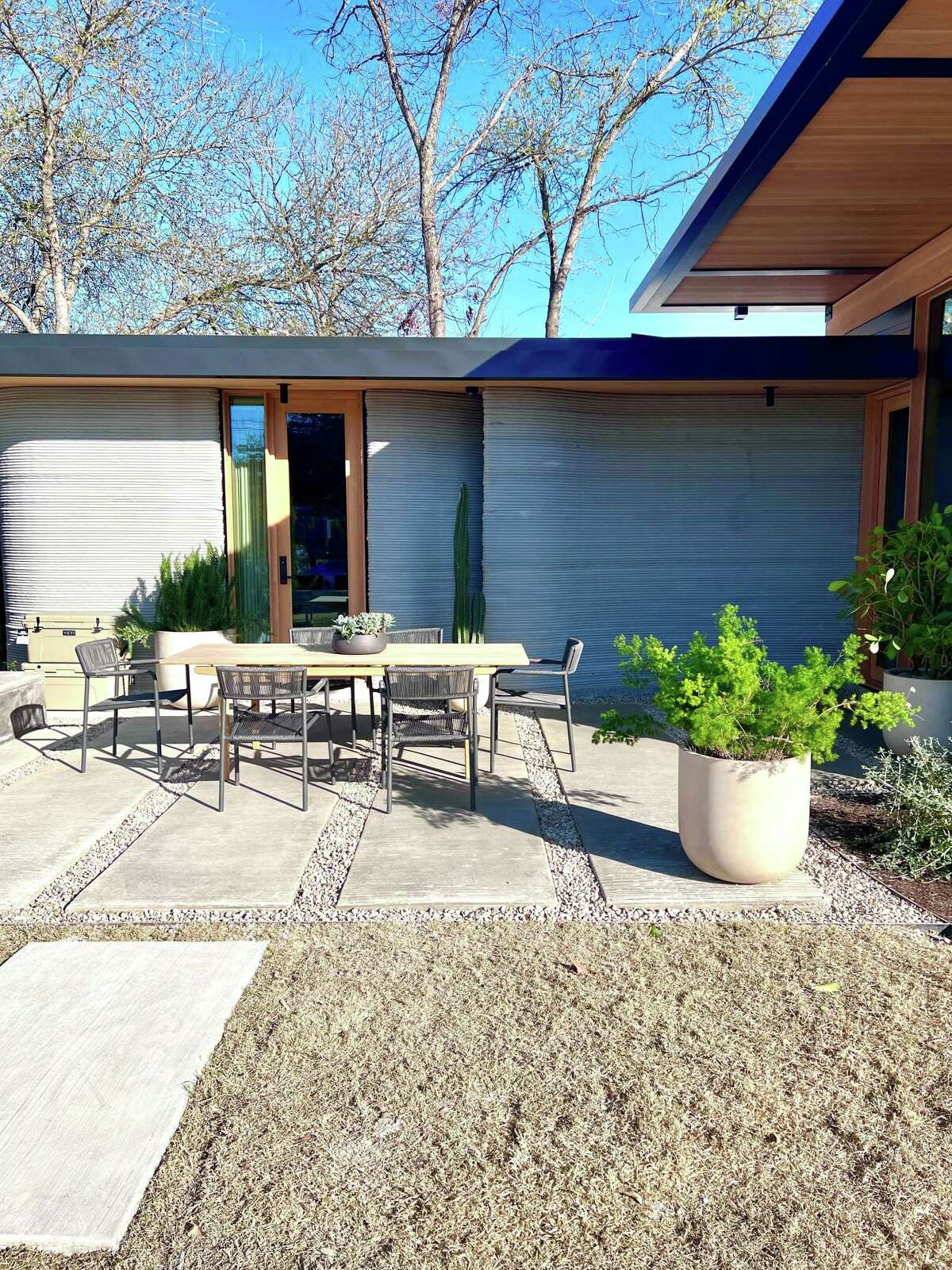 An outdoor living space between the 3D-printed house and the casita.