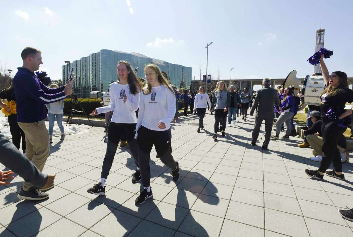 UAlbany women's basketball team members, Lilly Phillips, foreground left, from Greenwich, and Abby Ray, foreground right, from Saratoga Springs, along with other members of the team, walk out to their bus as they left campus on Wednesday, March 16, 2022, in Albany, N.Y. The team is headed off to Louisville, Ky. to take on the first-seed Louisville in the Women's NCAA Basketball Tournament.