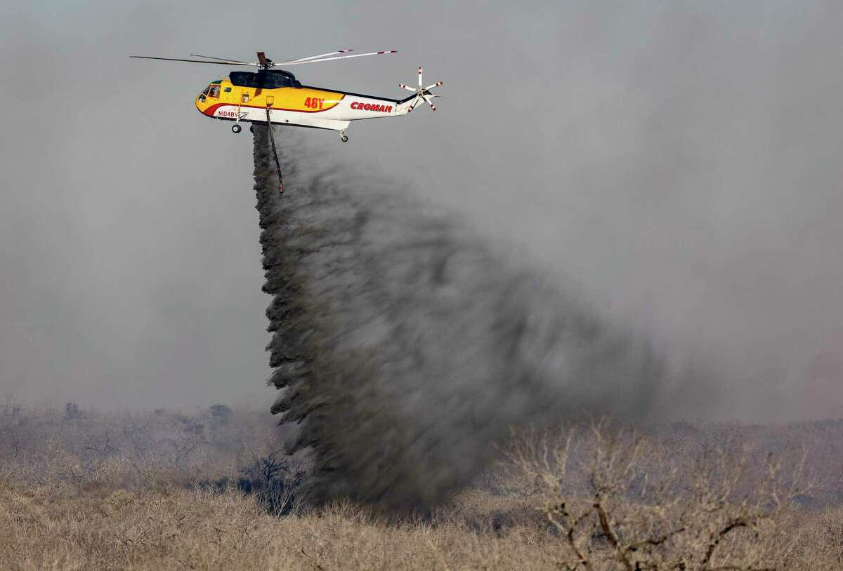A helicopter drops water Tuesday, March 15, 2022, on a wildfire south of Jourdanton in Atascosa County. In addition to area fire departments on the ground, the Texas Forest Service used one helicopter and two large tankers to fight the fire.