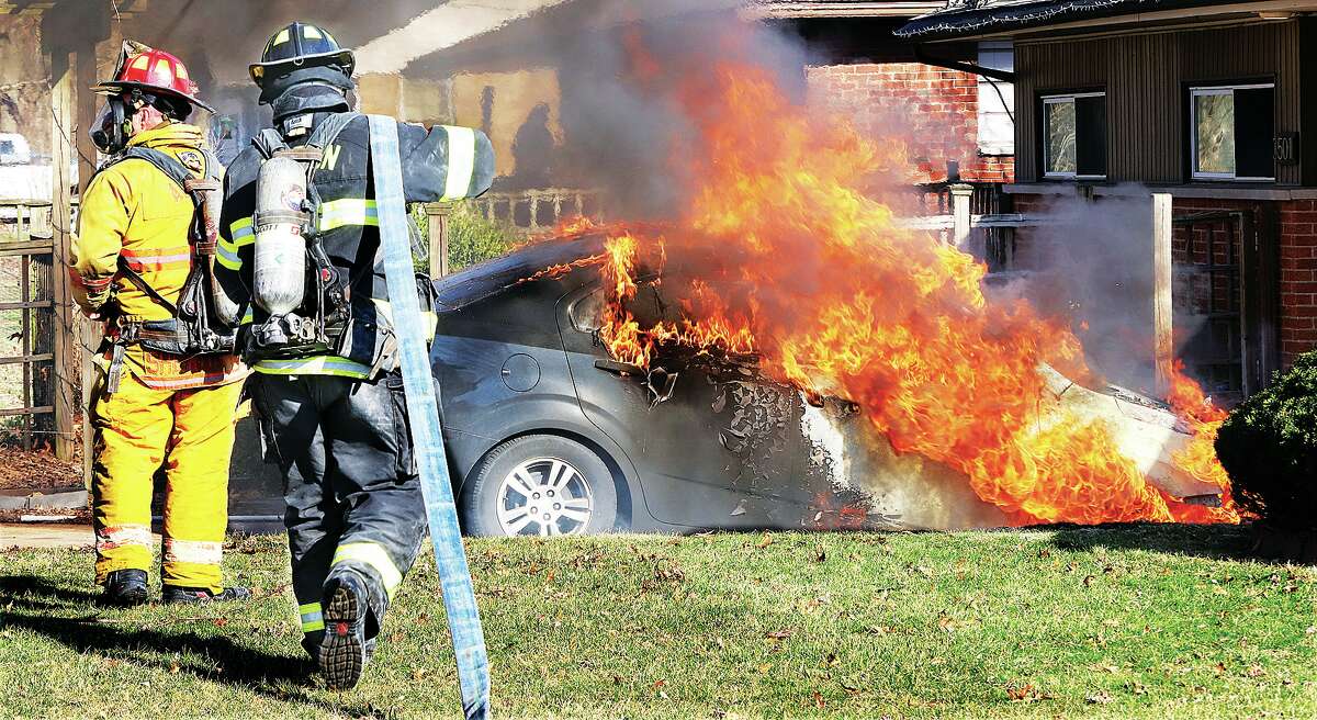 John Badman|The Telegraph Alton firefighters move in on a car fully involved in flames in the driveway of a house just before 5 p.m. Wednesday in the 3400 block of Meridocia Street. No injuries were reported but the car was a total loss.