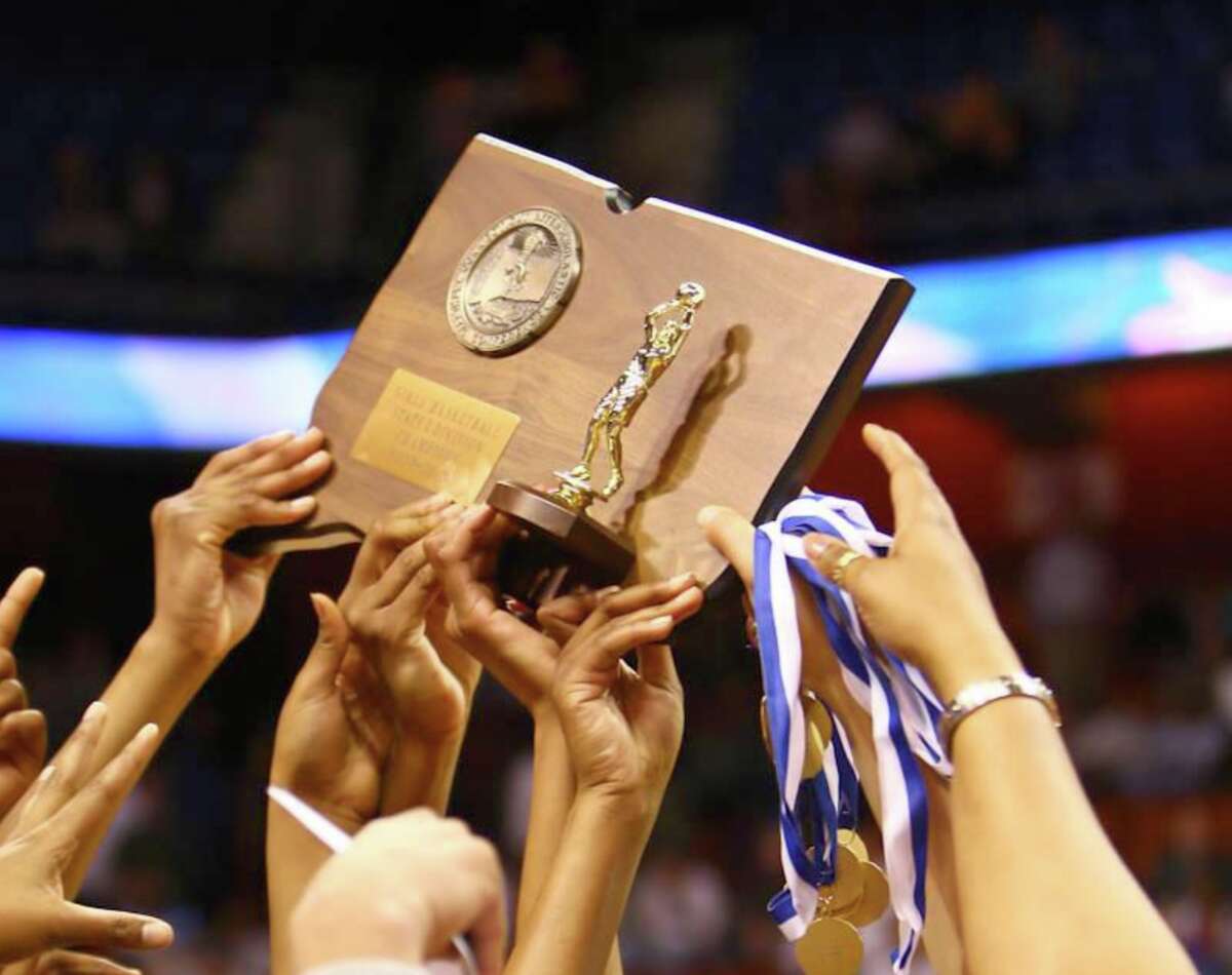 Players raise a state championship trophy at Mohegan Sun during one of the CIAC's basketball championships. 